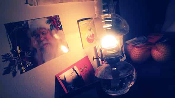 Oil-lamp illuminating a postcard featuring Santa Claus.