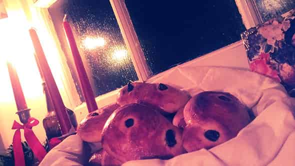 Saffron buns in a basket, on a windowsil illuminated by candlelight.