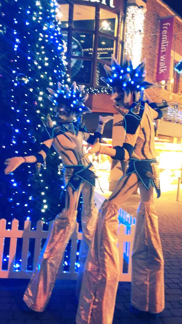 Maidstone Christmas Lights events, with two people on stilts dressed as white and blue Christmas trees.